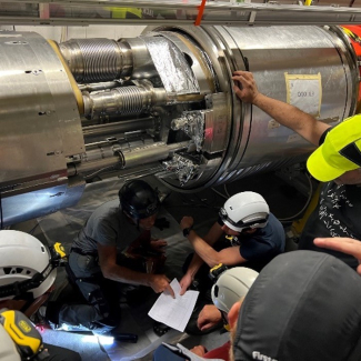Les techniciens et ingénieurs du CERN auscultent l’interconnexion défaillante entre des aimants triplets (en orange)